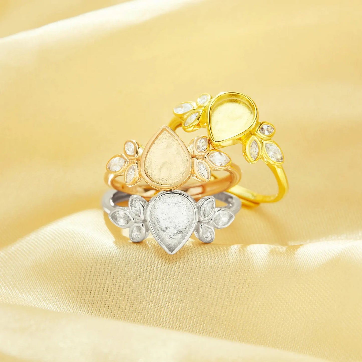 Two gold rings with heart-shaped stones on a yellow fabric background