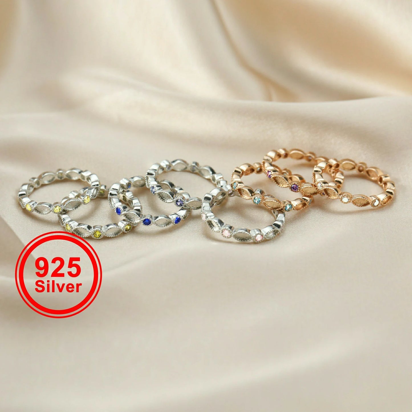 gold and silver rings with embedded stones on a beige fabric background, featuring a '925 Silver' label.