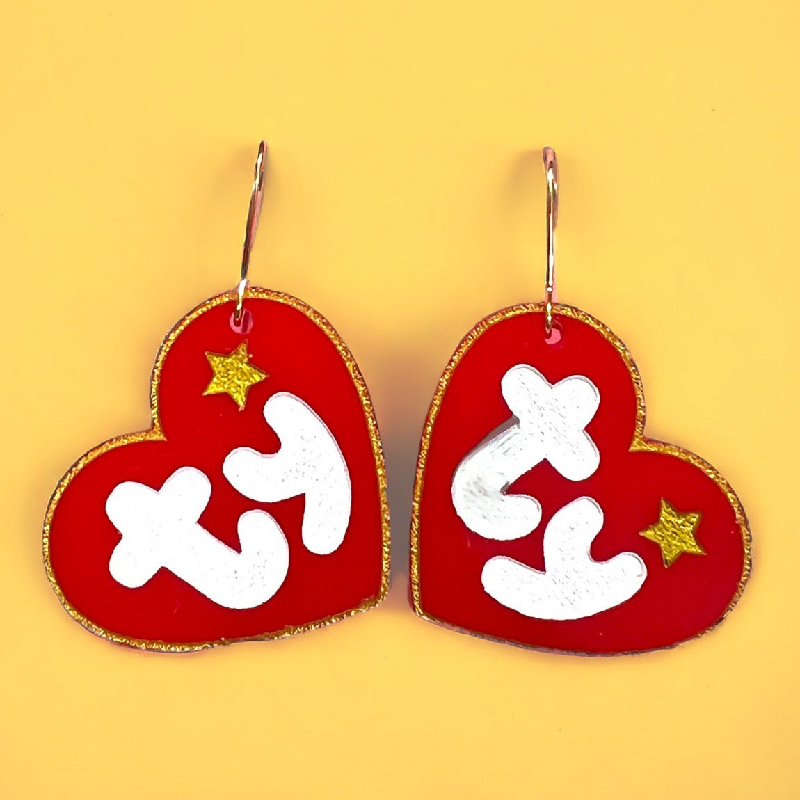 red heart shaped acrylic earrings made to look like a beanie baby tag with white ty and gold outline and small heart, on silver-plated hardware. perfect gift for the retro lover.