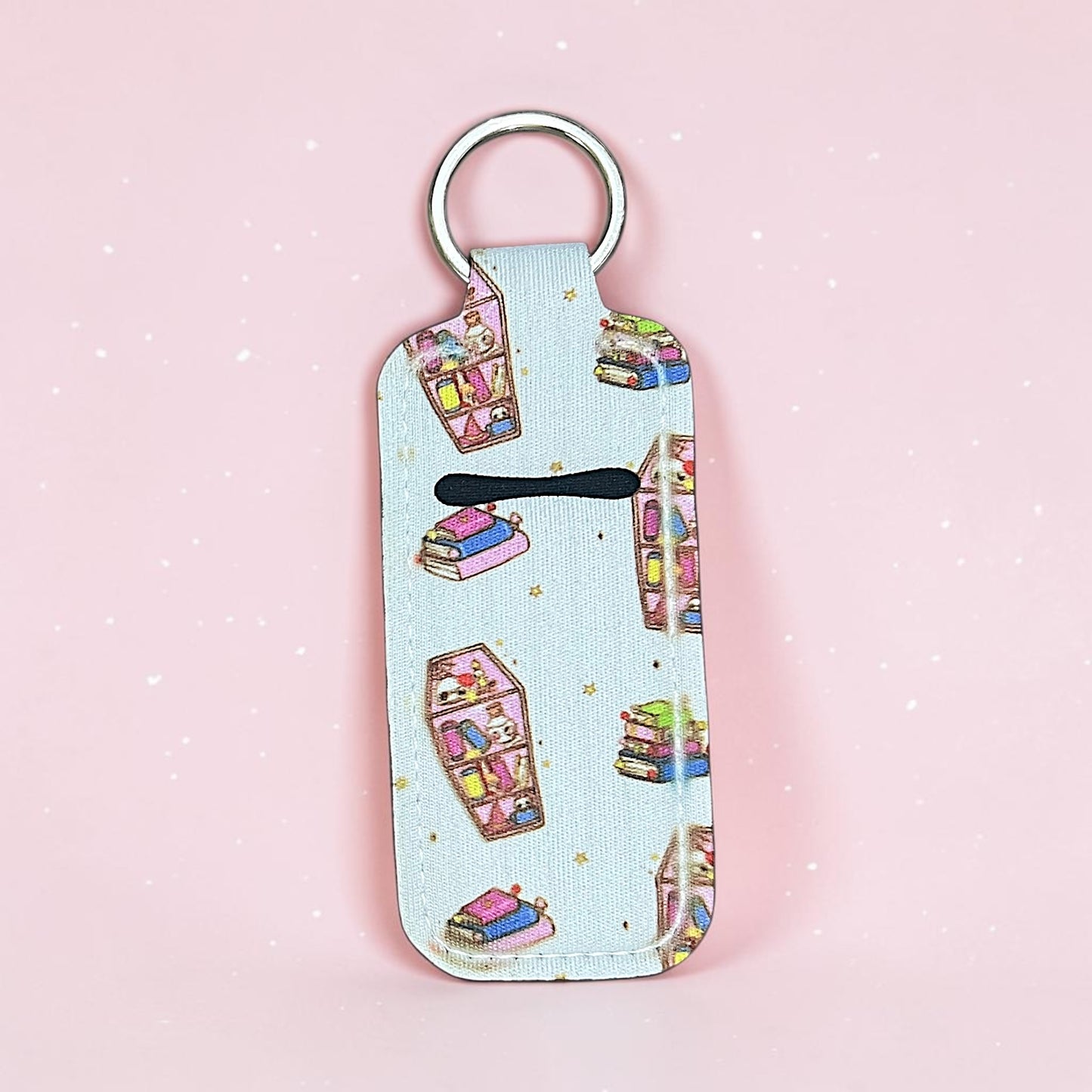 Keychain with book-themed design on a pink background