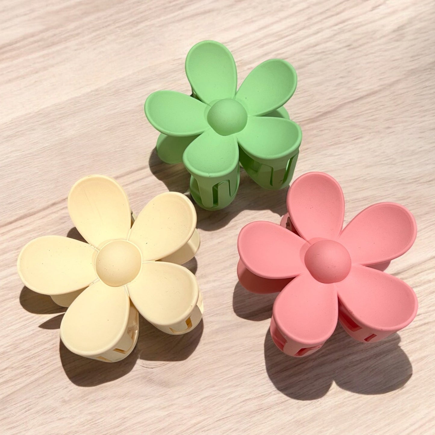 three daisy shaped claw hair clips in yellow green and pink