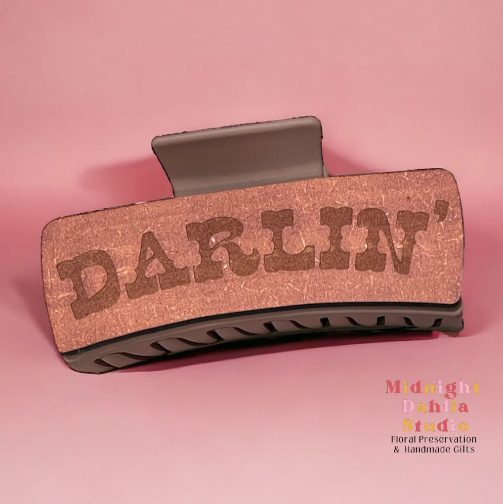 a claw clip with wood that has darlin' etched in it in an old-fashioned western font
