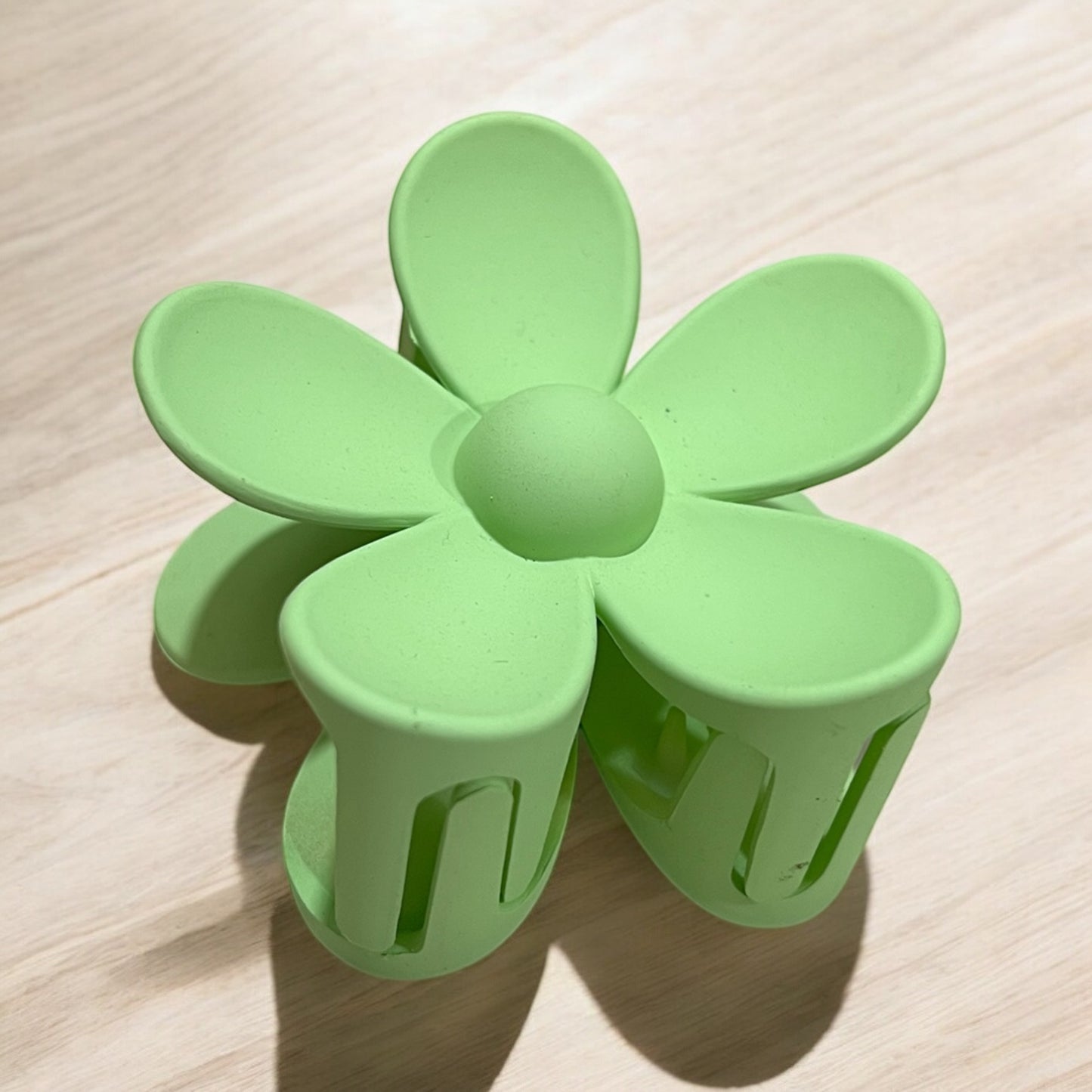 a daisy shaped plastic claw hair clip in green