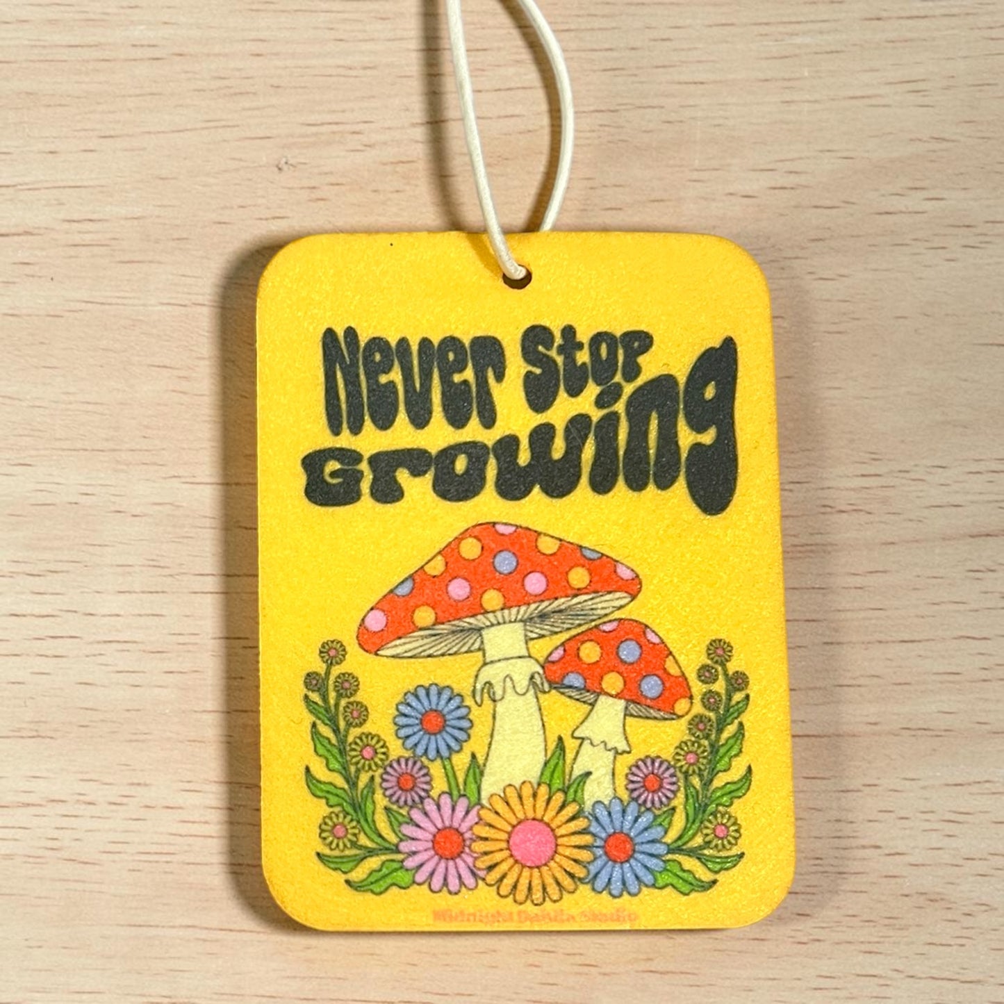 Yellow tag with mushrooms and flowers and 'Never Stop Growing' text