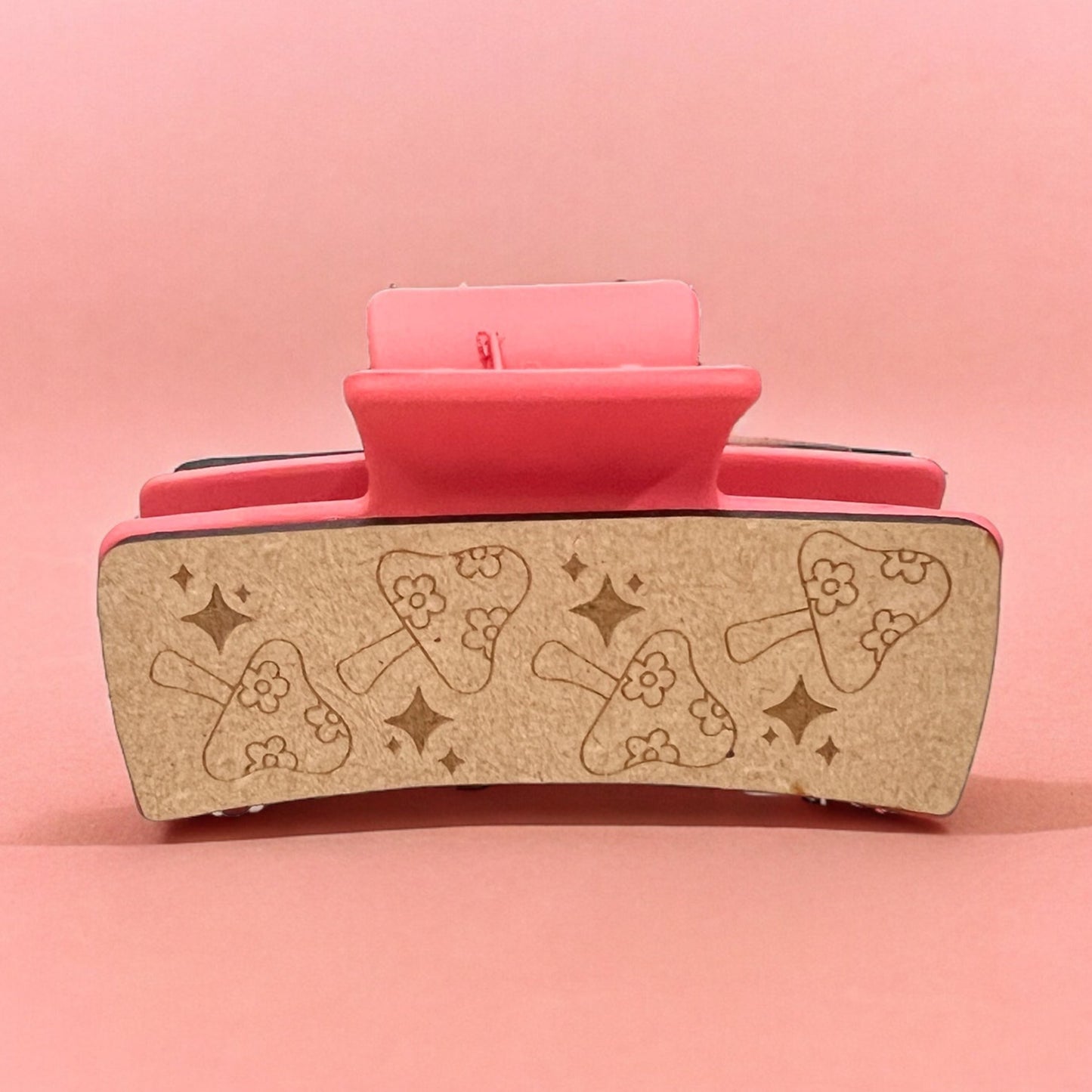 a claw clip with wooden outside with engraved mushrooms with daisies and stars