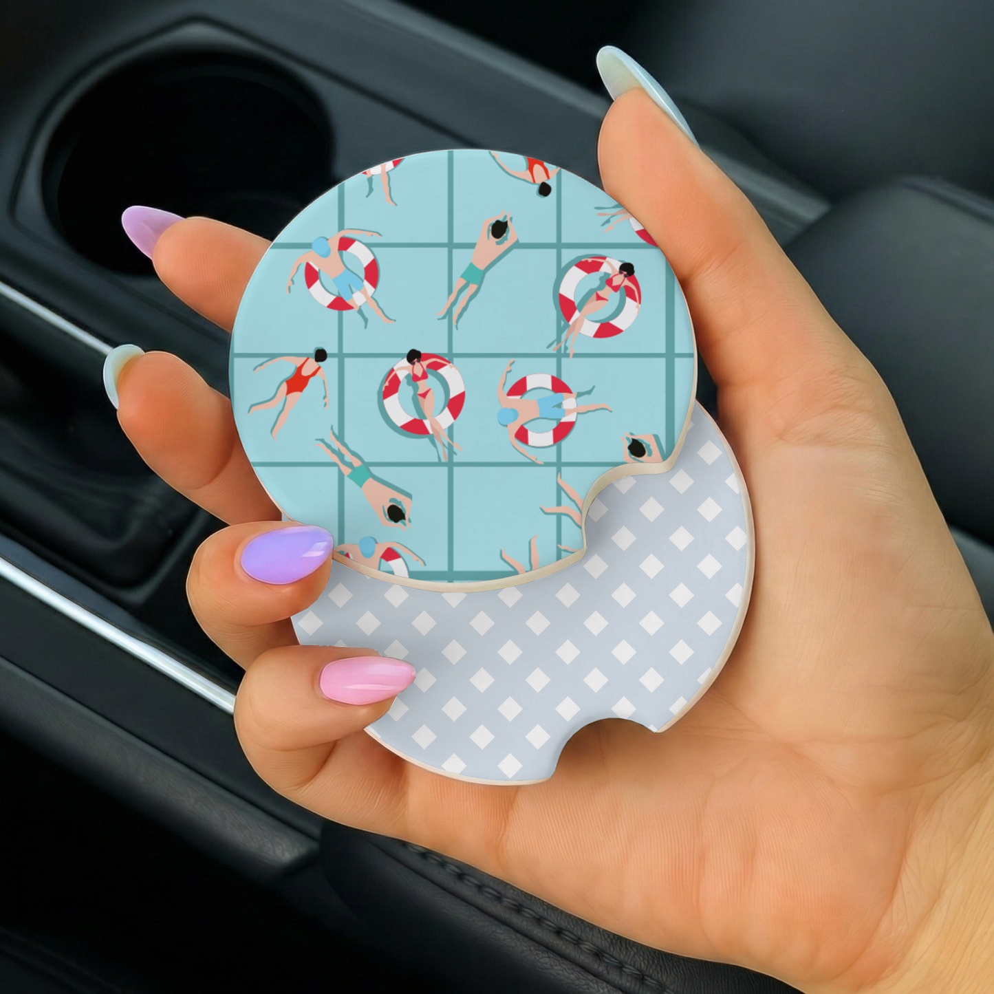 Hand holding a car coaster with a pool-themed design inside a vehicle.