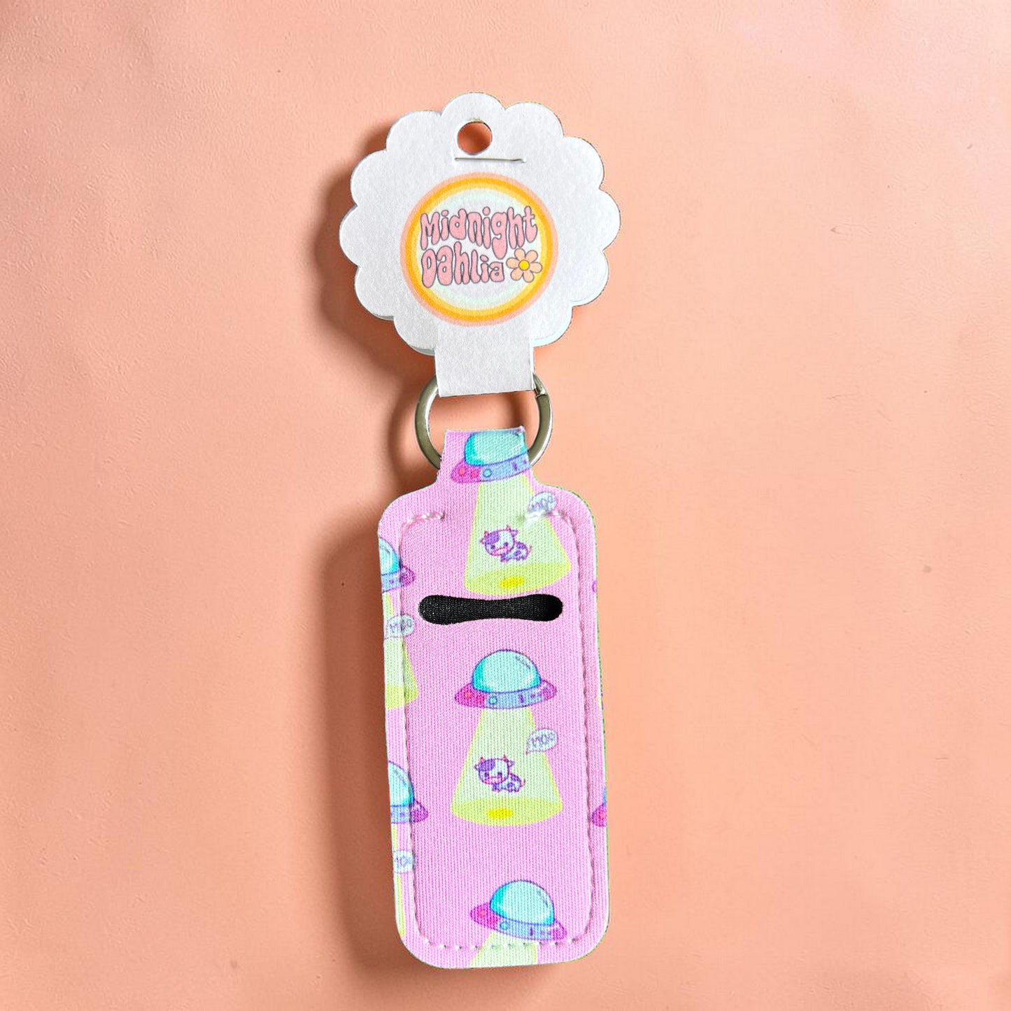 Pink keychain with alien design on a peach background