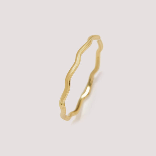 Gold ring with a wavy design on a light gray background