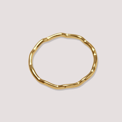 Gold ring with a unique design on a light gray background