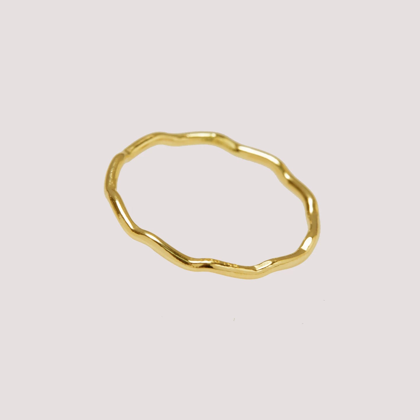 Gold ring with a textured surface on a light gray background