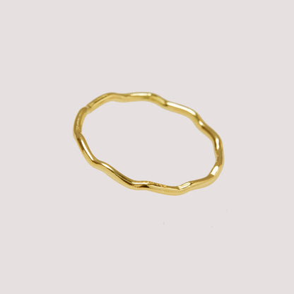 Gold ring with a textured surface on a light gray background