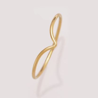 Gold infinity ring on a light pink background