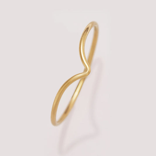 Gold infinity ring on a light pink background