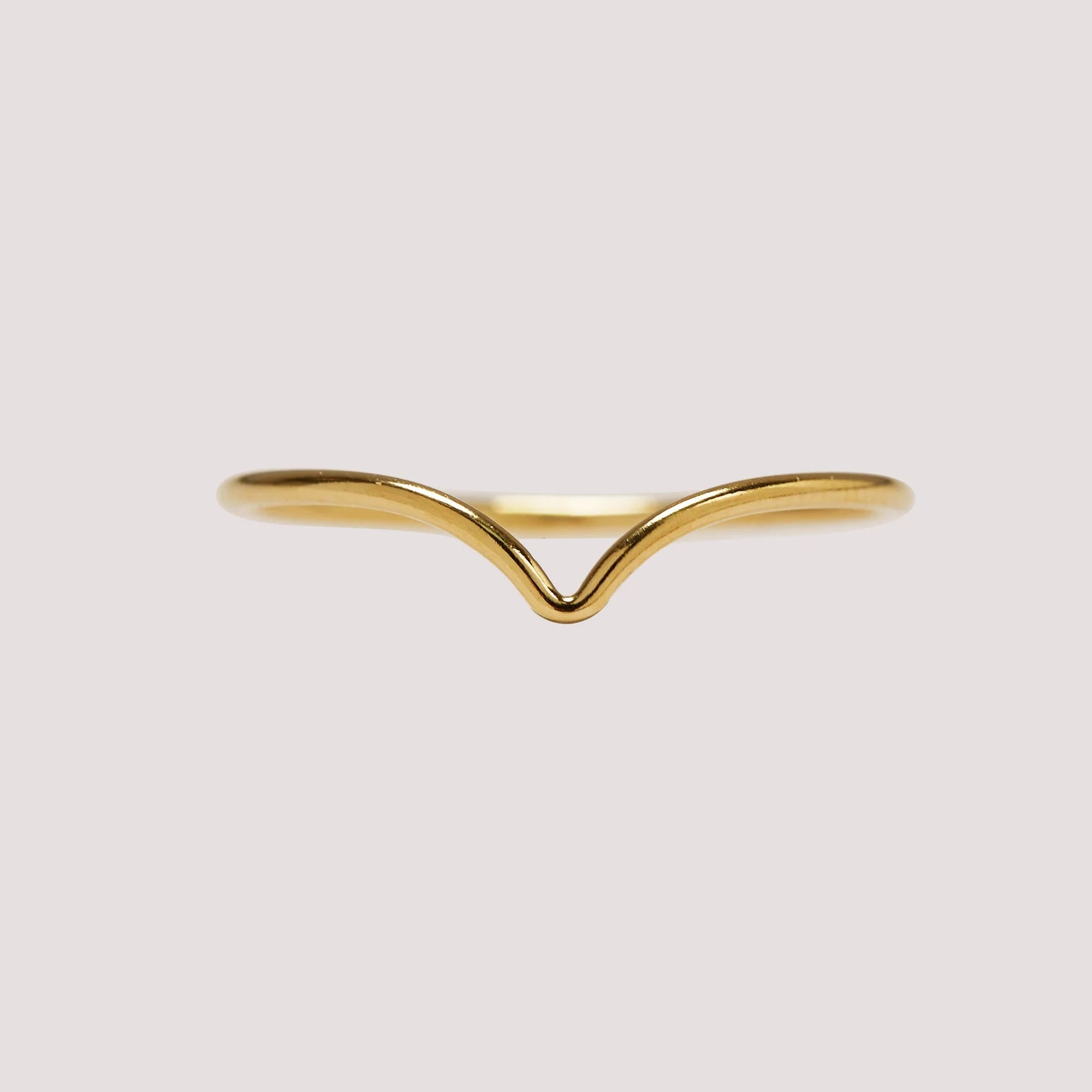 Gold ring with a wavy design on a light gray background