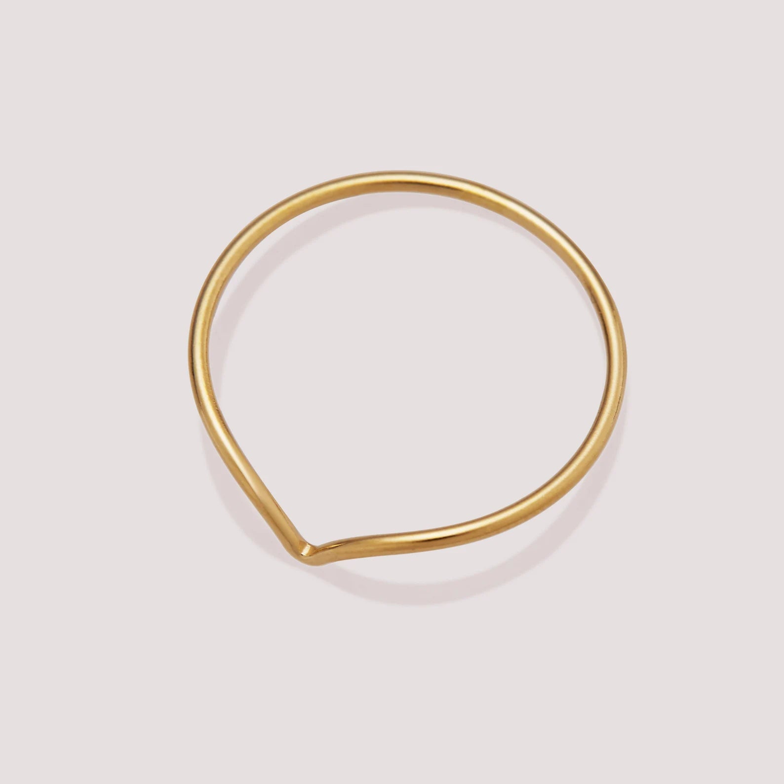 Gold teardrop-shaped ring on a light gray background