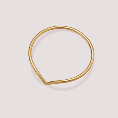 Gold teardrop-shaped ring on a light gray background