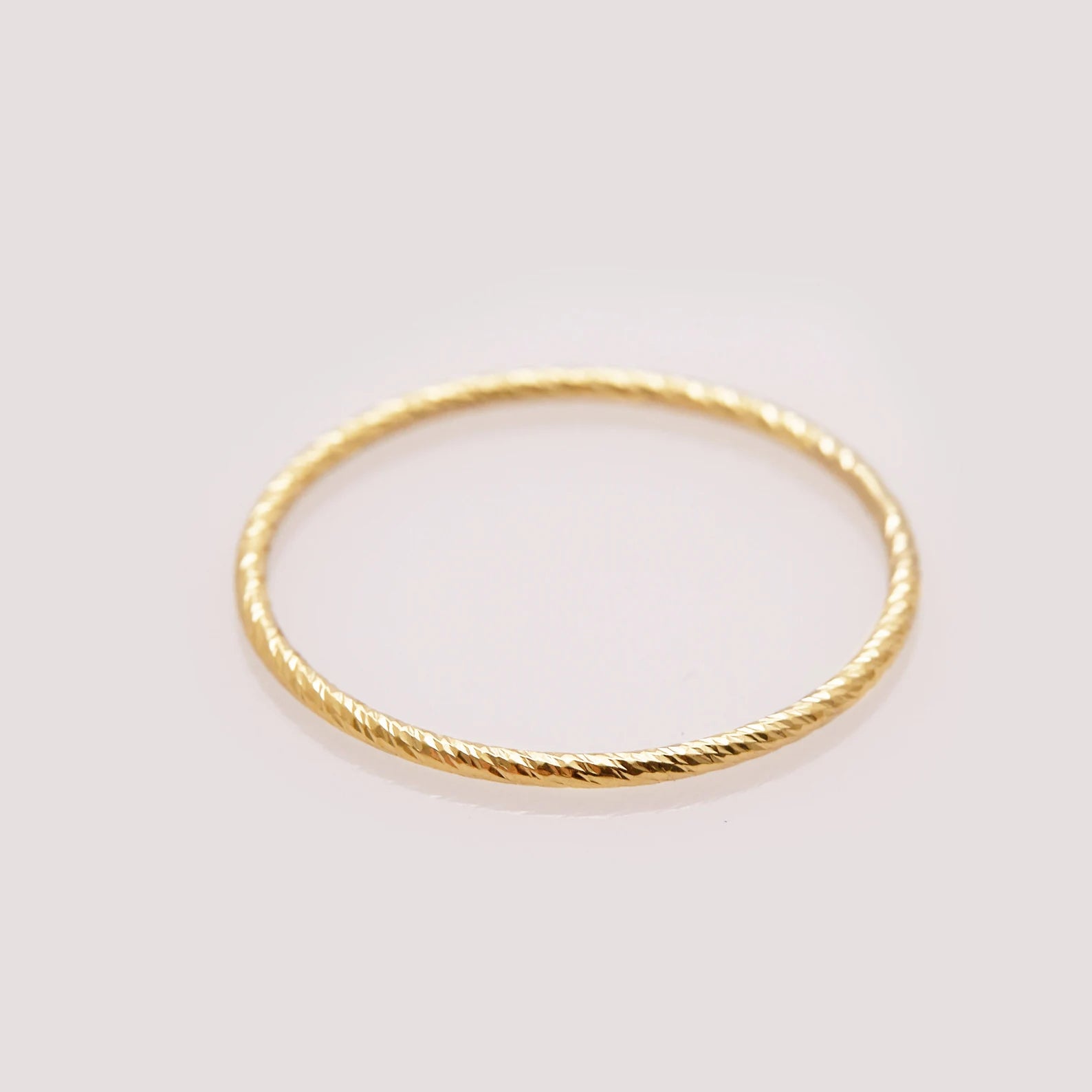 Gold ring with a textured band on a light gray background