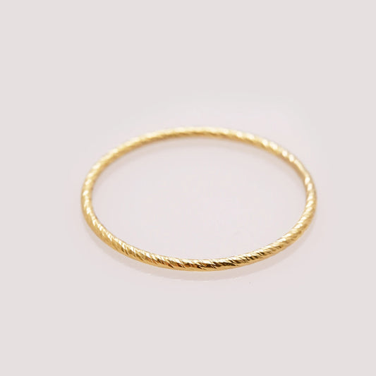 Gold ring with a textured band on a light gray background