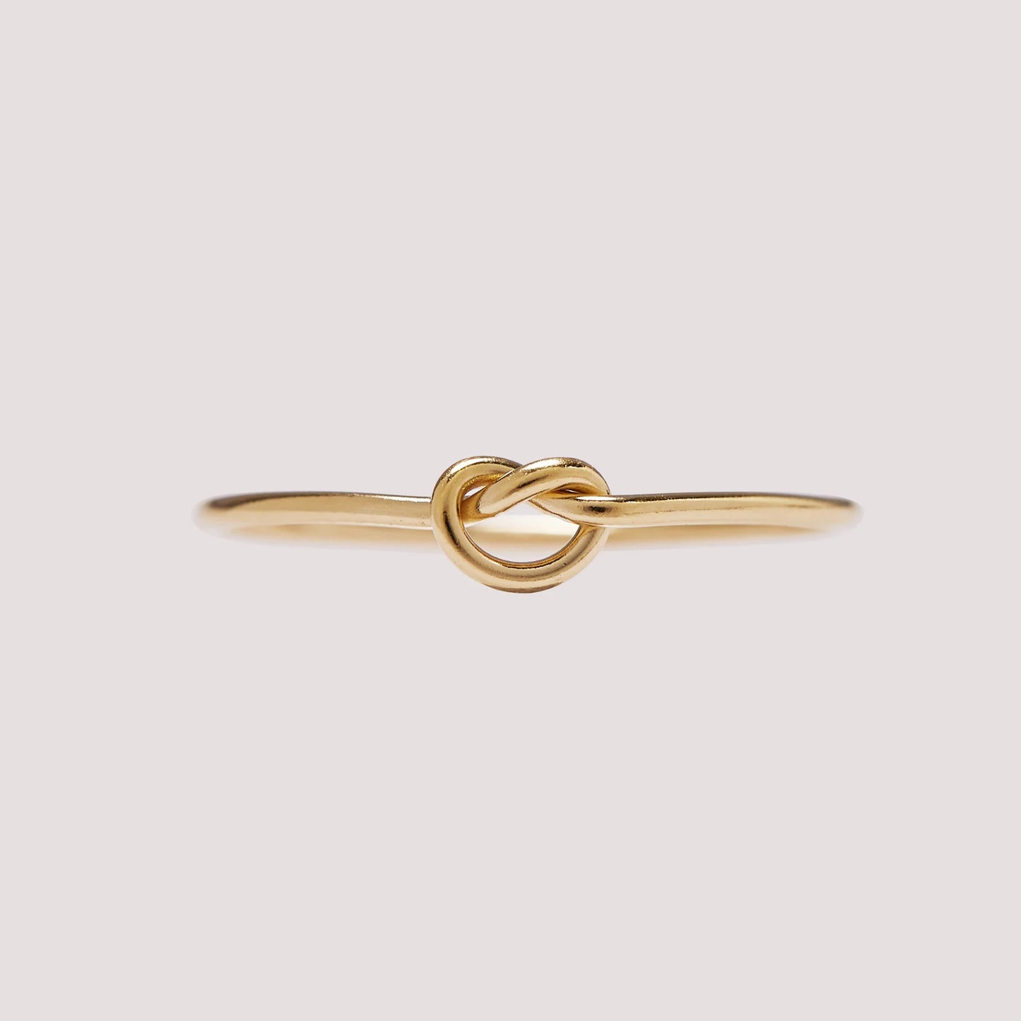 Gold knot ring on a light gray background