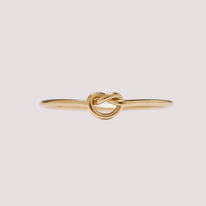 Gold knot ring on a light gray background