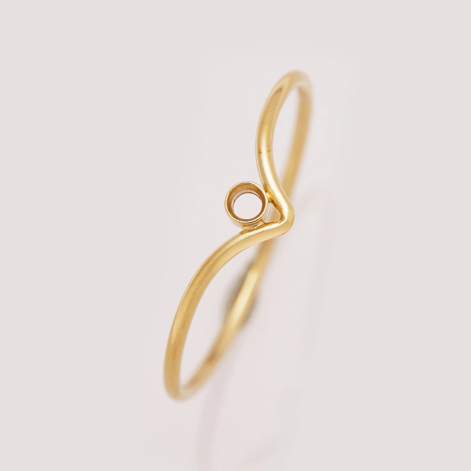 Gold ring with a unique design on a light gray background