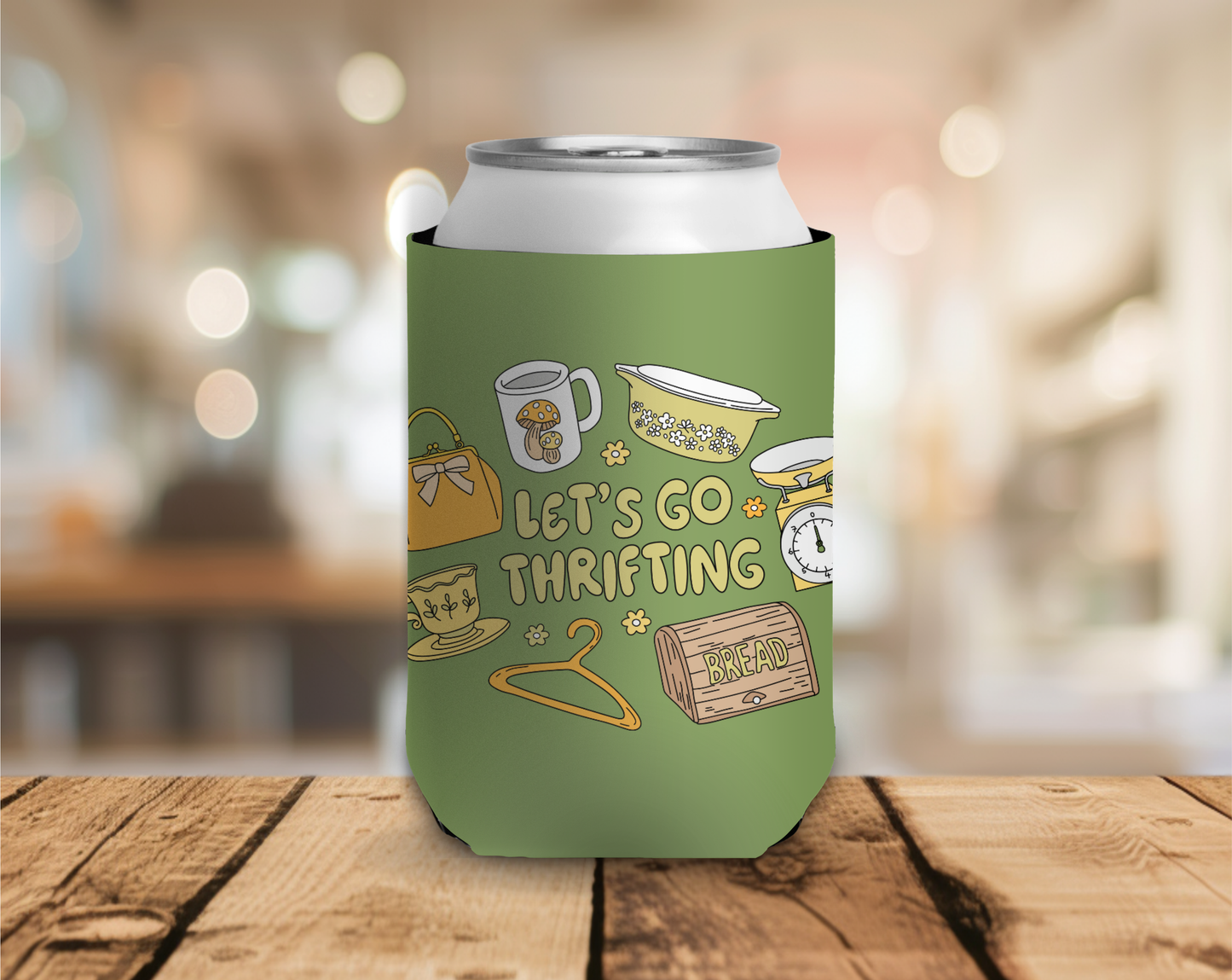 Green can cooler with 'Let's Go Thrifting' design on a wooden surface