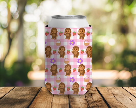 Can cooler with bigfoot and strawberry pattern on a wooden surface with a blurred natural background