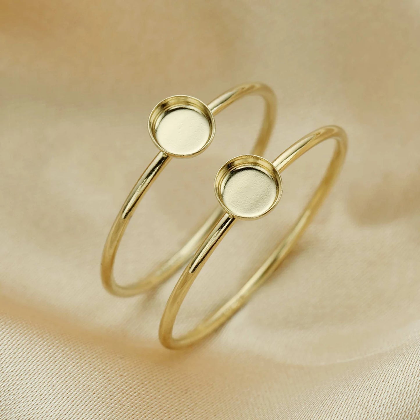 Gold bangles with round embellishments on a beige fabric background