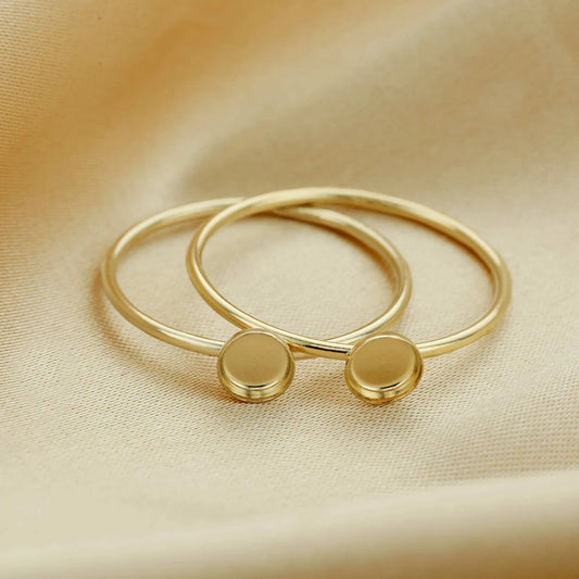 Gold bangles with round embellishments on a beige fabric background