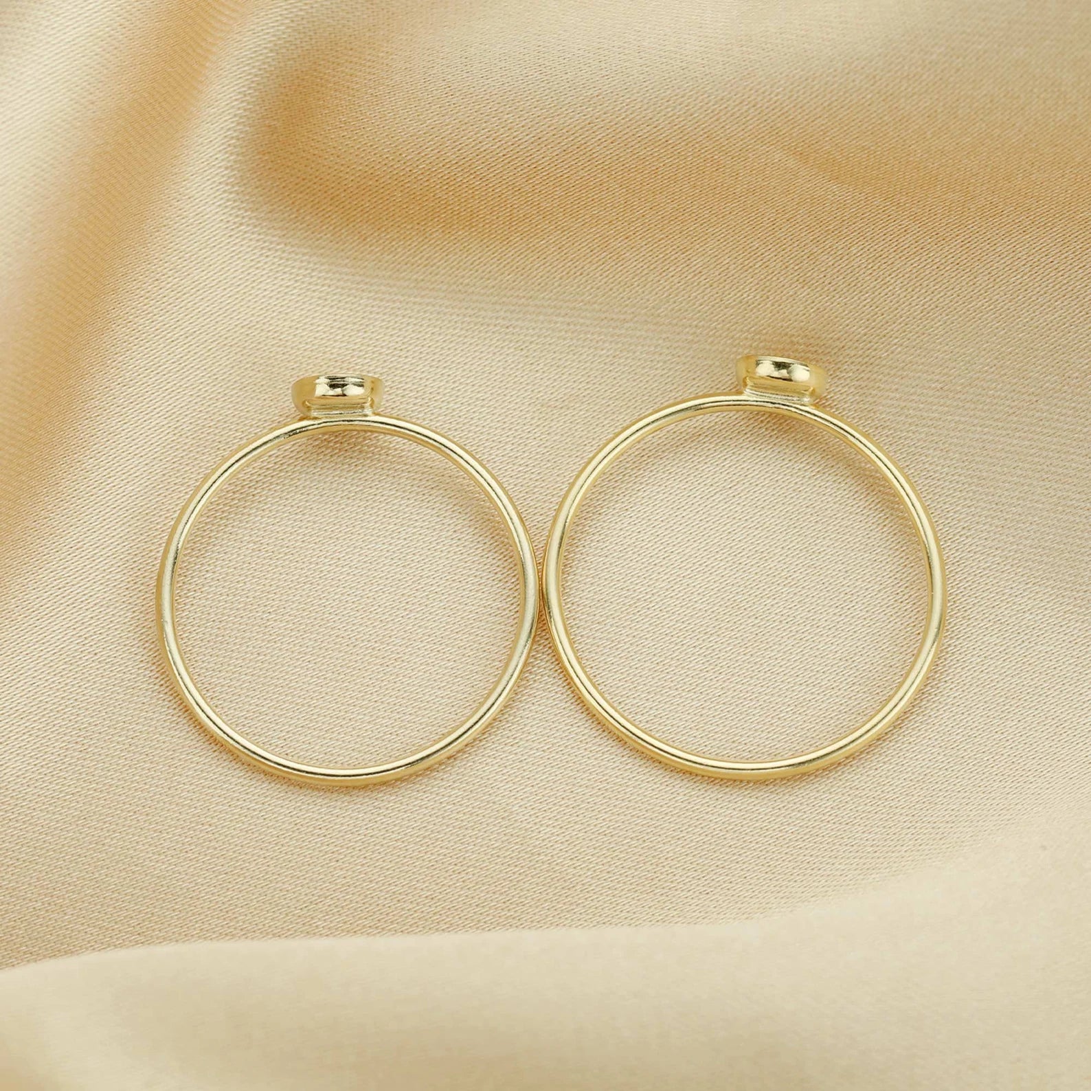 Gold hoop earrings on a beige fabric background