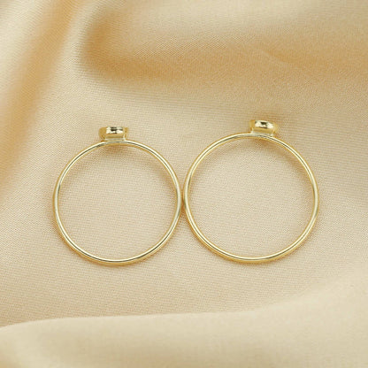 Gold hoop earrings on a beige fabric background