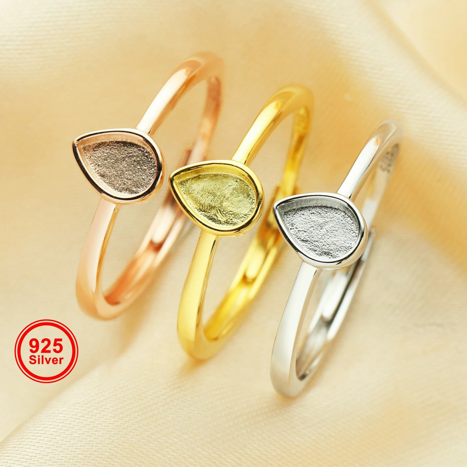Three silver rings with teardrop-shaped stones on a beige background, featuring '925 Silver' label.