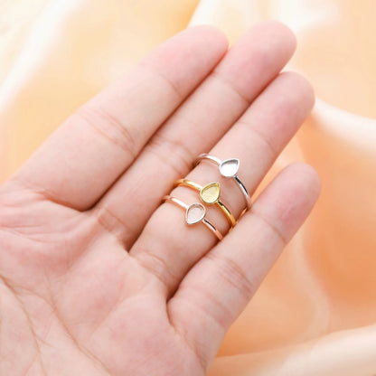Three heart-shaped rings on a hand against a soft peach background