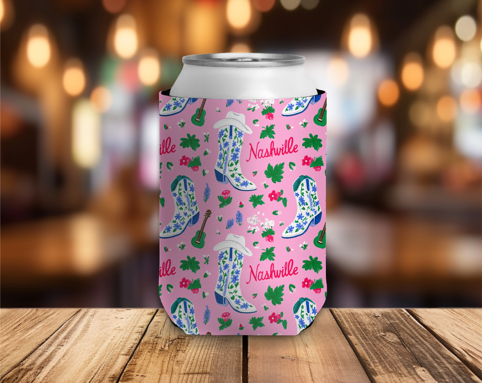 Pink can cooler with Nashville-themed design on a wooden surface with blurred background