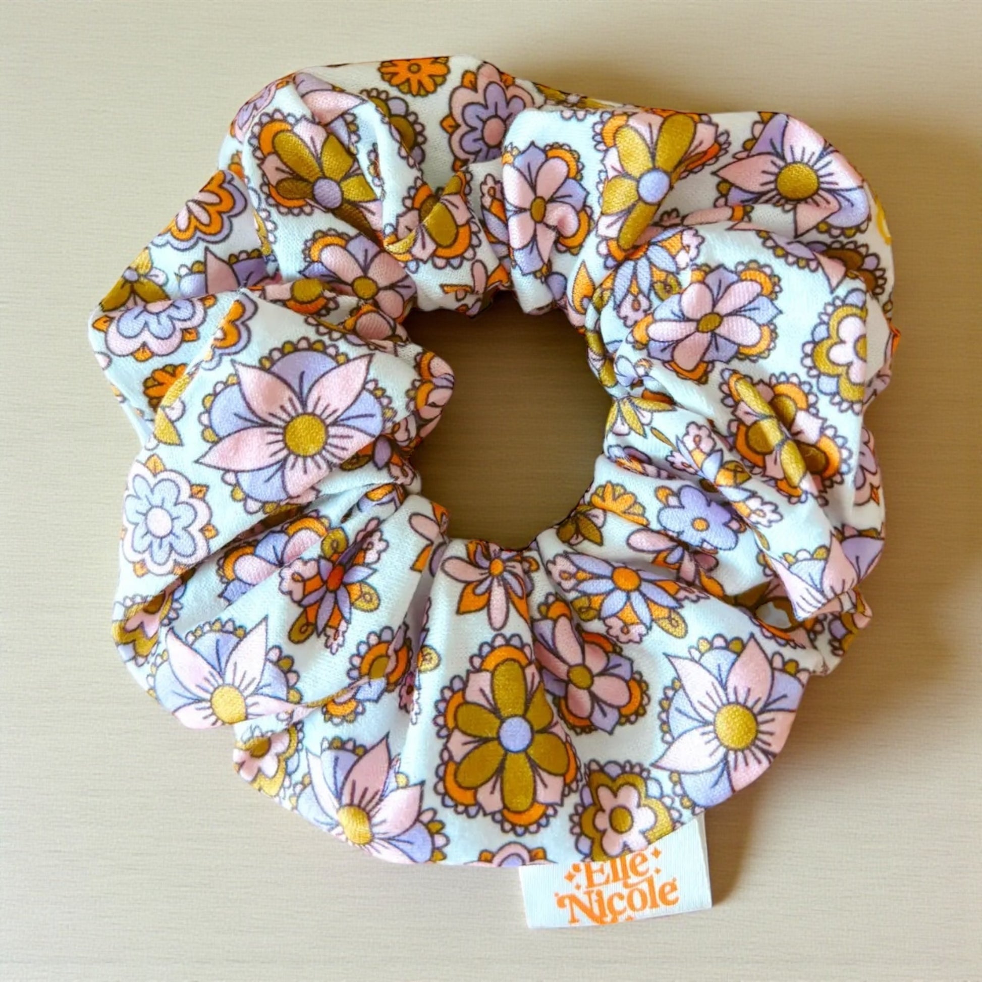 Floral patterned scrunchie with 'Little Nicole' branding on a beige background
