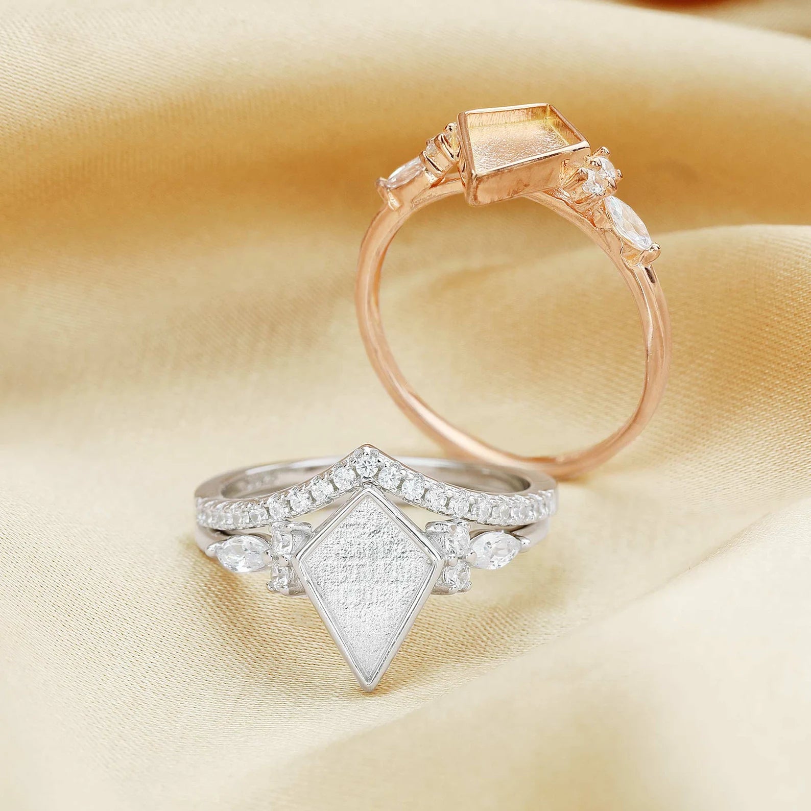 Two diamond rings on a beige fabric background