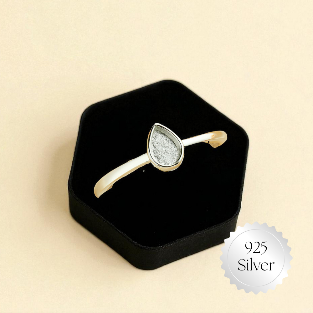 Gold ring with silver stone in a black box on a beige background