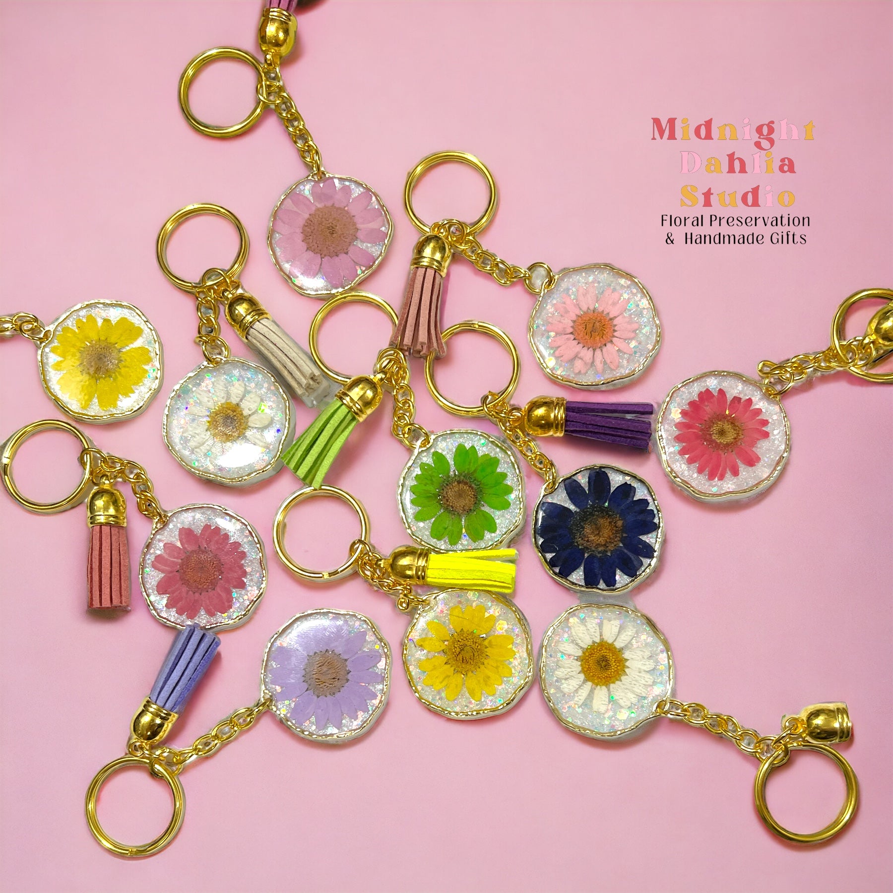 An assortment of real pressed flower keychains with multicolor daisies daisy and gold hardware.  Great gift for women woman and teen.