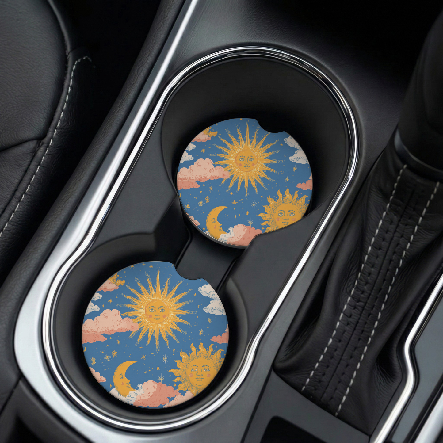 Two sun-themed car coasters in a cup holder of a black car.