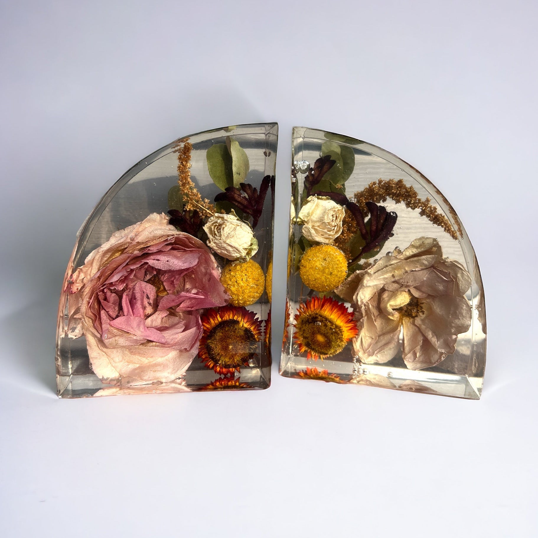 Custom resin bookend set made with white flowers included fall colors with orange and yellow strawflower , yellow billy balls craspedia , white spray mini roses , rust brown amaranthus , burgundy red kangaroo paw , and pink mauve roses.  A flower preservation option that is useful home decor forever.
