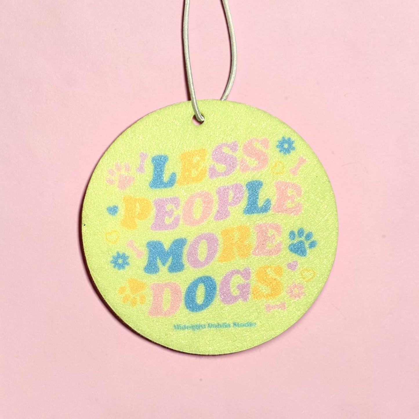 Round green tag with colorful text 'LESS PEOPLE MORE DOGS' on a pink background
