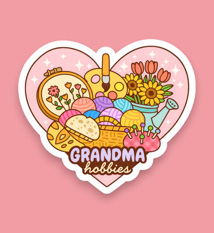 Heart-shaped sticker with various hobbies items and 'Grandma hobbies' text on a pink background