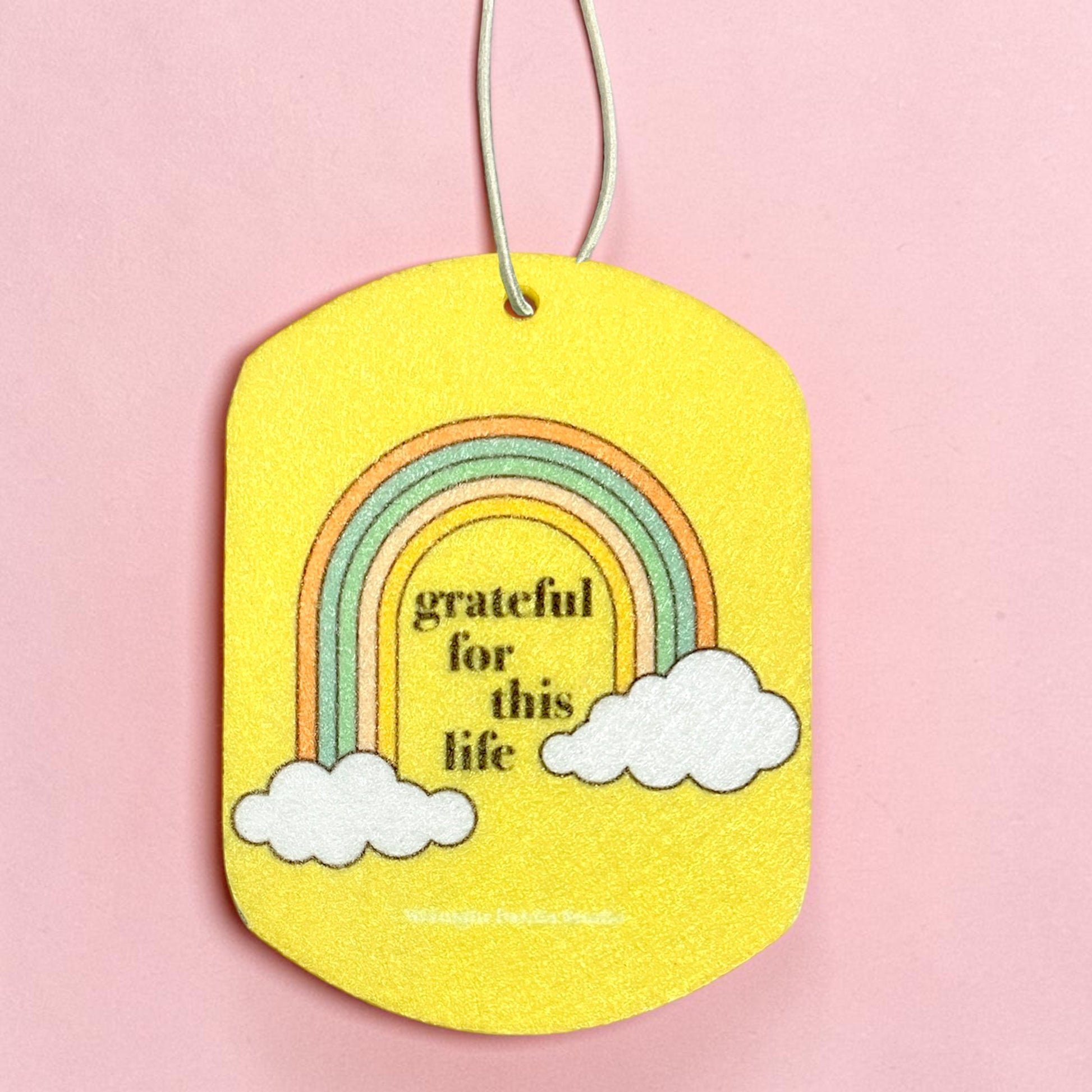 Yellow tag with rainbow and clouds design on a pink background