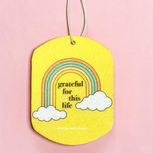 Yellow tag with rainbow and clouds design on a pink background