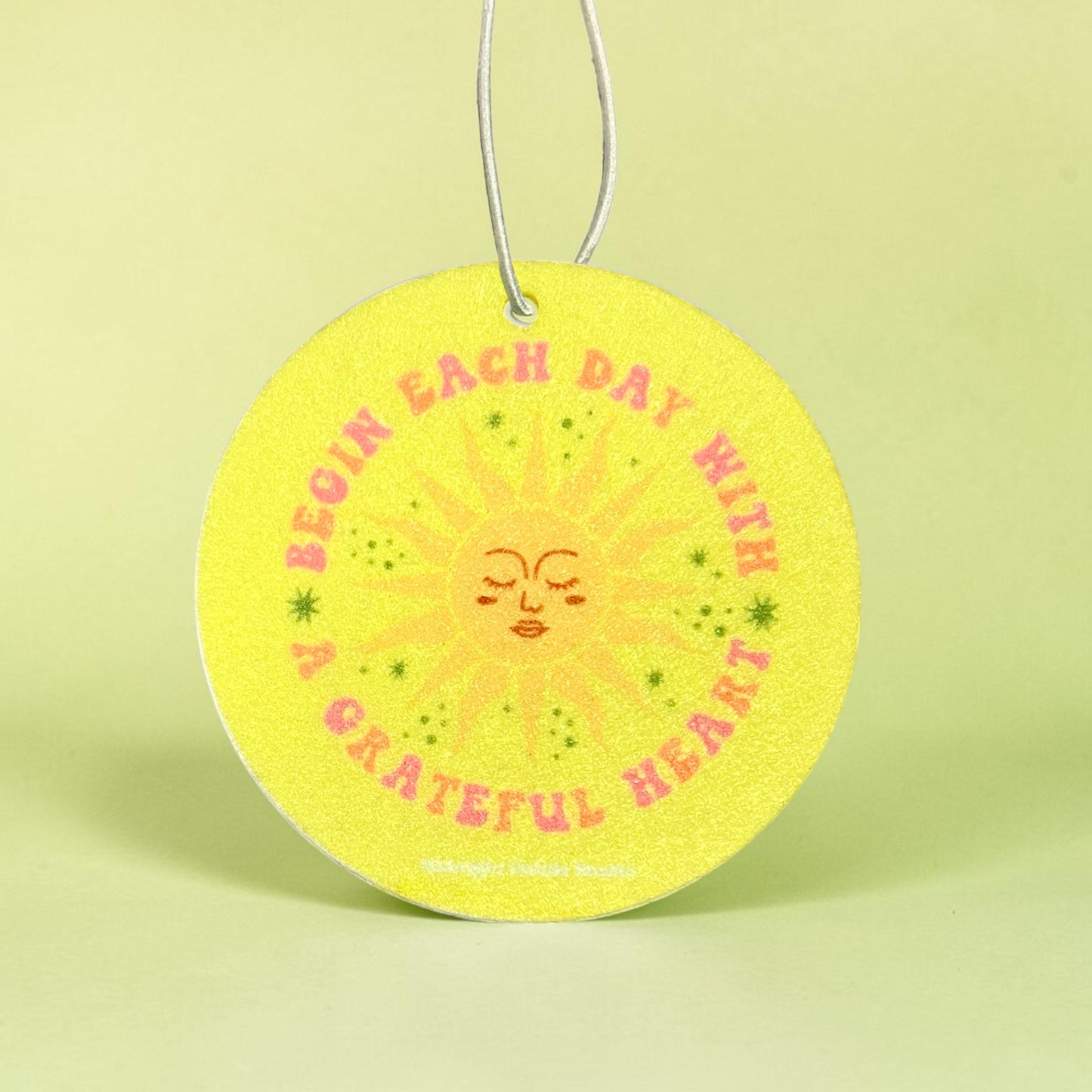 Circular yellow magnet with sun design and text on a light green background