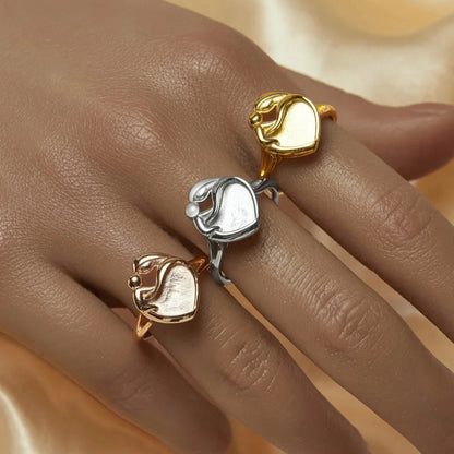 Three gold and silver rings on a hand against a beige fabric background