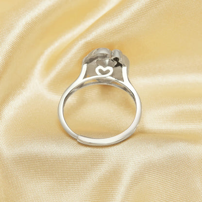 Silver ring with a heart-shaped design on a beige satin background