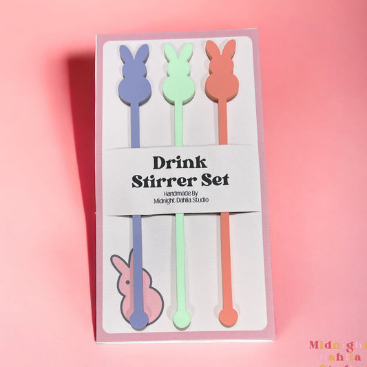 Three peep bunny shaped drink stirrers in lavender purple, light pale green, and a light pink coral for easter.
