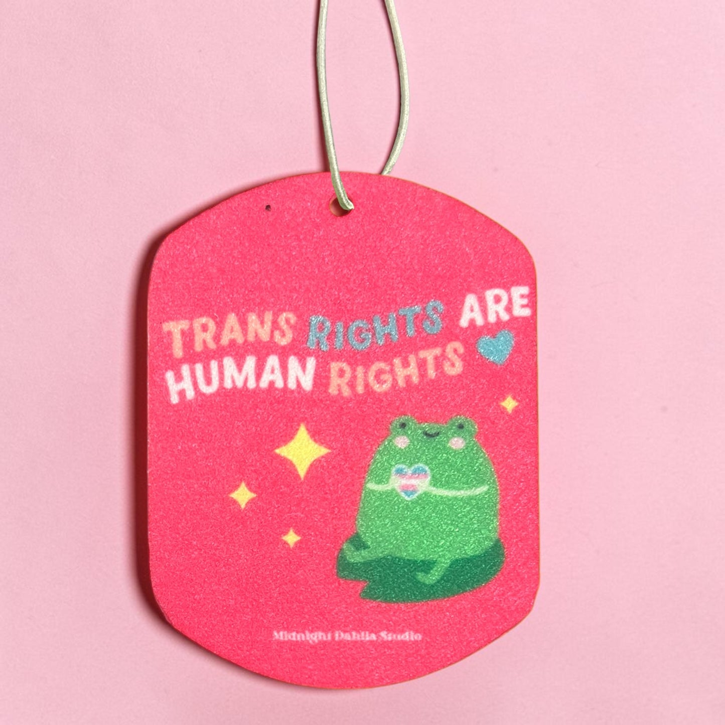 Pink air freshener with a green frog illustration and text on a pink background