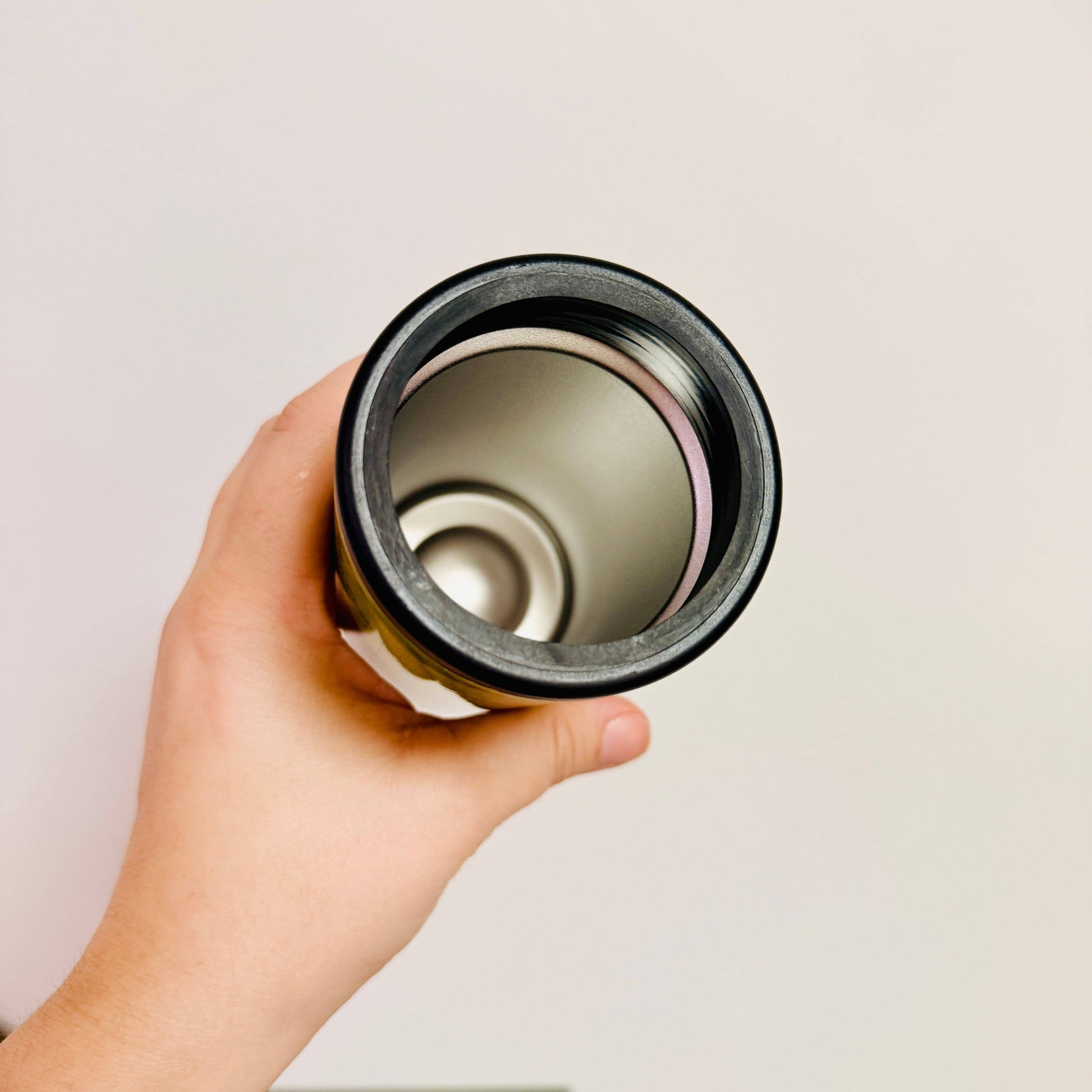 Hand holding a cylindrical object against a plain background